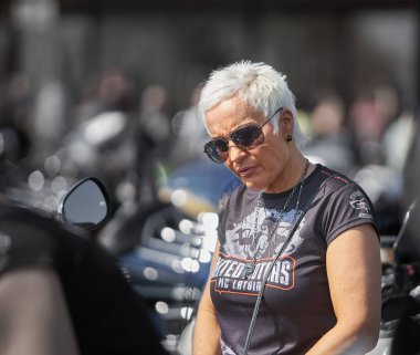 24-04-2019 Riga, Letonya. Motosikletin tepesinde oturan olgun sarışın kadın.