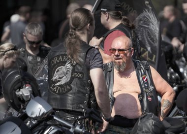 24-04-2019 Riga, Letonya. Dövmeli motorcu diğer motorcularla konuşuyor.