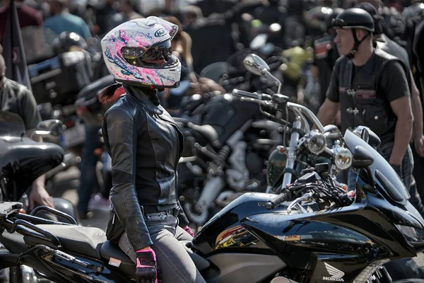 24-04-2019 Riga, Letonia. Chica motorista en una chaqueta de cuero y casco en una motocicleta — Foto de Stock