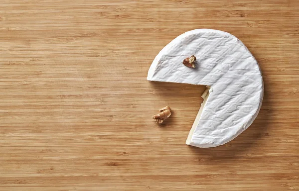 Queijo camambert com nozes e manjericão sobre tábua de corte de madeira — Fotografia de Stock