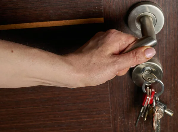 Vrouw hand open een deur. Sleutels hangen in slot — Stockfoto