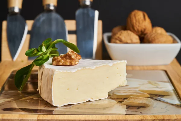 Close-up de queijo e nozes na placa de queijo de madeira . — Fotografia de Stock