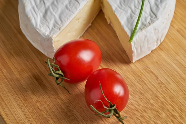 Queijo e tomate na mesa de madeira. Atirar de perto — Fotografia de Stock