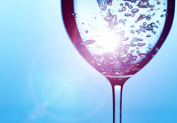 A bubble splash of transparent clear water liquid in glass on a light blue background at sunlight — Stock Photo, Image