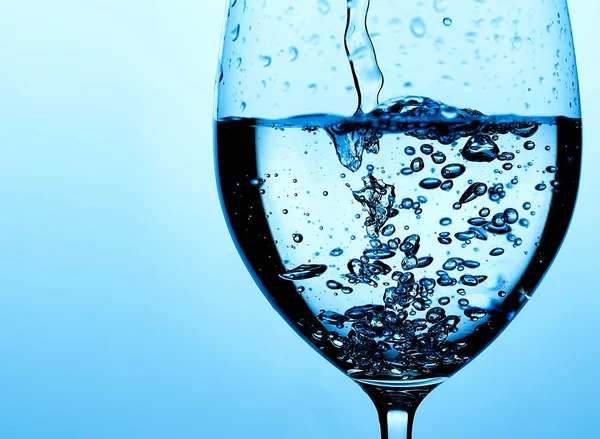 Closeup photo of pouring pure water in glass. Light blue background — 스톡 사진