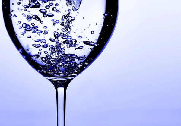 Pouring water into a glass against light blue background — 스톡 사진