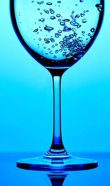 Pouring water into a glass against light blue background — 스톡 사진