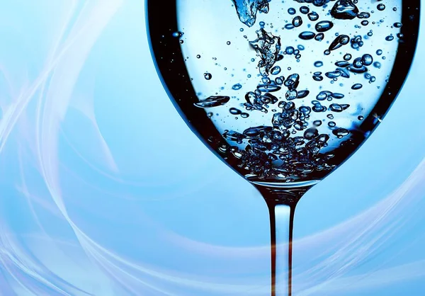 Pouring water into a glass against light blue background — 스톡 사진