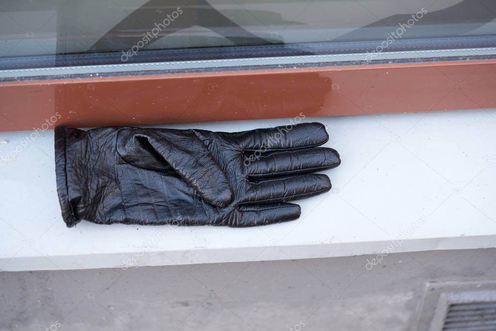Old black leather gloves lie on a stone.