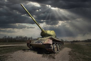 Old Soviet tank T-34 of World War II, running on the grass field in rays of sun.