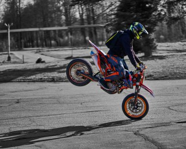 23-04-2020 Riga, Letonya Motosikletlisi çapraz motosikletle ön tekerleğe biniyor.