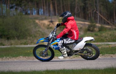 10-05-2020 Ropazi, Letonya motosikletçisi boş asfalt yolundaki süpermoto turlarında. Motosiklet antrenmanı hızlı bir viraja dayanıyor..