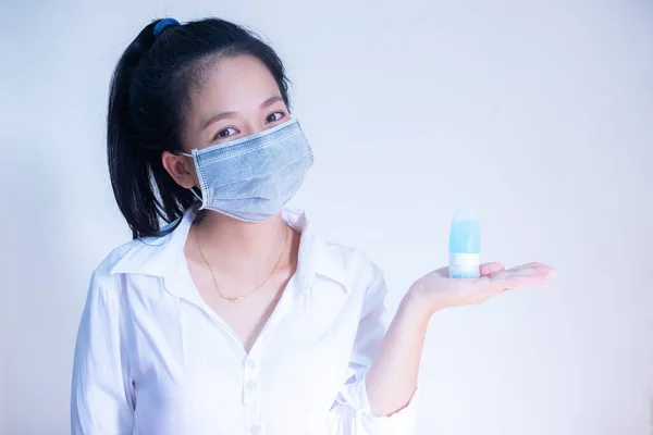 Kadın hijyenik koruyucu maske takıyor elinde alkol dezenfektanı jeli beyaz arka planda fotokopi alanı ile duruyor, Corona virüsüne karşı günlük koruma veya COVID-19 konsepti.