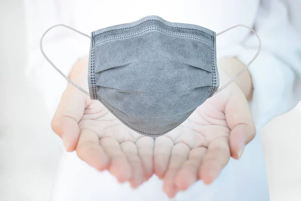 Doktor elinde antivirüs maskesi tutuyor. Korunma, hava hastalıkları, grip ve Corona virüsüne karşı koruma, ya da Covid-19, tüm dünyaya yayılıyor. İnsan burnu ve ağzı için tıbbi maskeler. Kavram