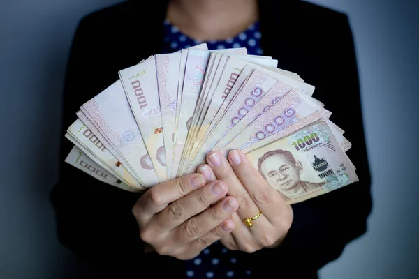 Gri arkaplandaki banknotları tutan kadın elleri.