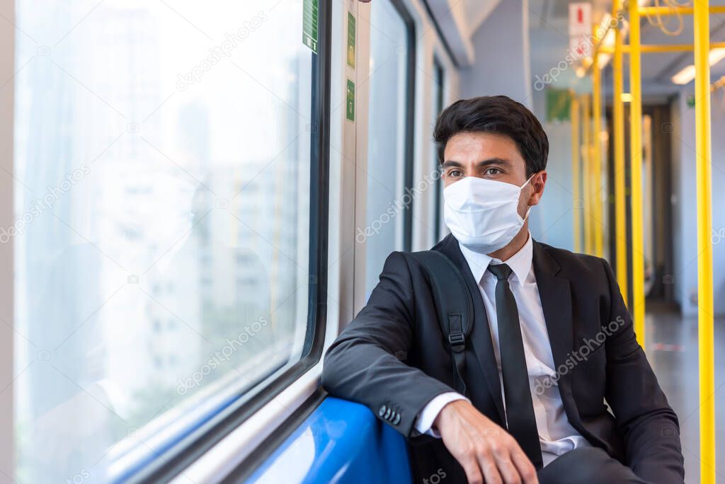 Businessman wearing white facial mask during travel by train sit near window, new normal life style during covid-19 pandemic with no people on train
