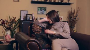 Kahverengi takım elbiseli Avrupalı hamile bir kız evinde koltukta uyuyor..