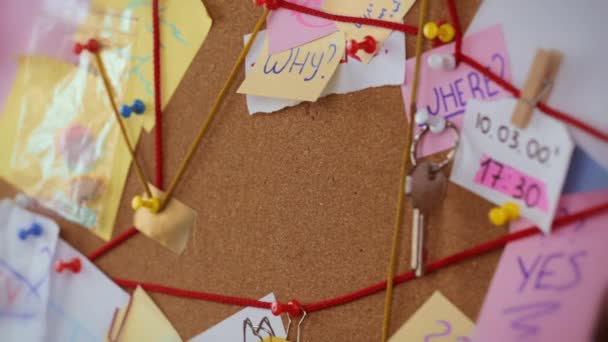 Travel search concept. Close-up view of a detective board with evidence. In the centerGirls hand pins a white sheet of paper with the inscription travel — Stock Video