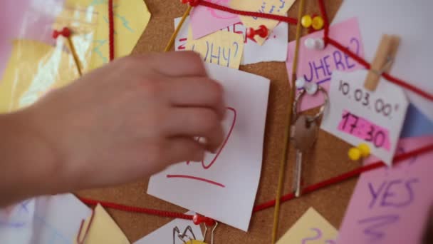 Concepto de decisión. Vista de cerca de una junta de detectives con pruebas. En el centro La mano de la niña arranca una hoja con la inscripción NO y clava un pedazo de papel con el texto SI — Vídeo de stock