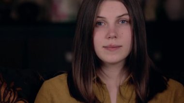 Yakın plan beyaz görünümlü güzel bir kadın bir sandalyeye oturup gülümseyerek öpücükler savuruyor. Sosyal Medya Günlük Kavramı