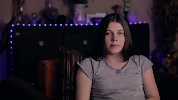 Ein junges Mädchen europäischen Aussehens sitzt zu Hause in einem Sessel und versucht ein Video aufzunehmen. erfolglose oder fehlgeschlagene Aufnahme von Videoaufnahmen. Social-Media-Blogging-Konzept. — Stockvideo