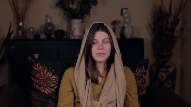 Una joven mujer cristiana bonita con un pañuelo en la cabeza, de aspecto caucásico, se sienta en un sillón y graba un video vlog. Concepto de Blogging en Redes Sociales . — Vídeo de stock