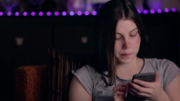 Retrato de uma jovem sentada na cadeira conversando no celular em um quarto acolhedor. Encantadora atmosfera doméstica — Vídeo de Stock