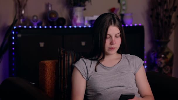 Retrato de uma jovem sentada na cadeira conversando no celular em um quarto acolhedor. Encantadora atmosfera doméstica — Vídeo de Stock