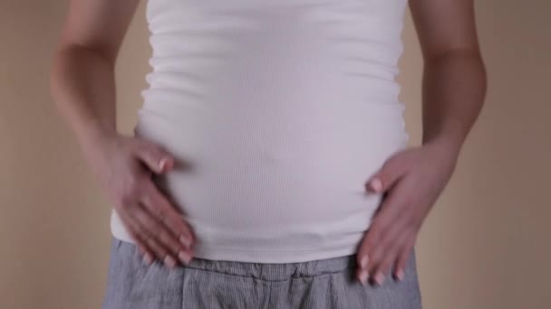 Conceito engraçado. Uma visão de perto da barriga de uma mulher grávida em uma camiseta branca que treme a barriga — Vídeo de Stock