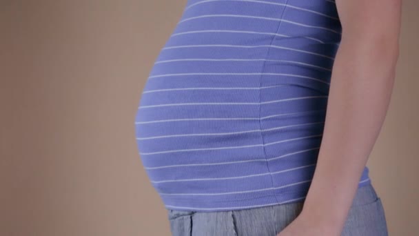 Mavi tişörtlü hamile bir kadının göbeğinin yakın plan görüntüsü. Broşürlerde yazılı olan broşürleri tutuyor ve evet. Hamilelik sırasında seyahat kavramı. — Stok video