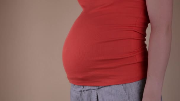 Una vista de cerca del vientre de una mujer embarazada con una camiseta azul, que muestra el éxito a mano y sostiene un pedazo de papel con la inscripción SI. Mujer embarazada feliz — Vídeos de Stock