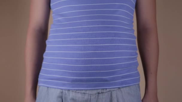 Eine Nahaufnahme des Bauches einer schwangeren Frau in einem blauen T-Shirt, das ein ähnliches Zeichen zeigt. Kopierraum für Text — Stockvideo