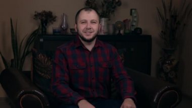 Avrupalı görünümlü bir blogcu olan etkili Sakallı Genç, ekose gömlekli bir sandalyede oturuyor ve herkesin videoyu sevmesini istiyor. Sosyal Medya Günlük Kavramı.