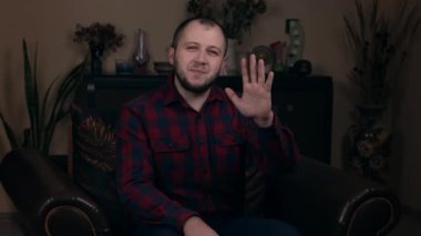 Avrupalı görünümlü bir blogcu olan etkili Sakallı Genç, ekose gömlekli bir sandalyede oturmuş bir video kaset kaydediyor. Sosyal Medya Günlük Kavramı.