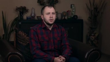 Avrupalı bir blogcu olan güçlü Sakallı Genç, ekose gömlekli bir sandalyede oturuyor ve video kaydetmeden önce gergin. Sosyal video günlüğü kavramı.