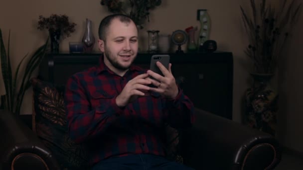 Un jeune homme d'apparence européenne s'assoit sur une chaise en chemise à carreaux, communique par liaison vidéo. Répond aux questions des abonnés. Le concept des blogs de réseaux sociaux . — Video