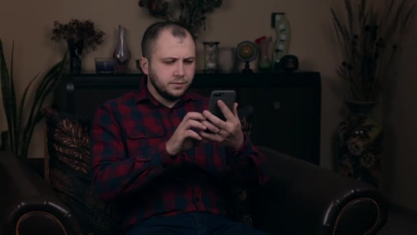 Los hombres sorprendidos leyendo el mensaje a través de teléfono inteligente. Muchacho molesto sosteniendo el teléfono celular en casa. Concepto de malas noticias — Vídeos de Stock