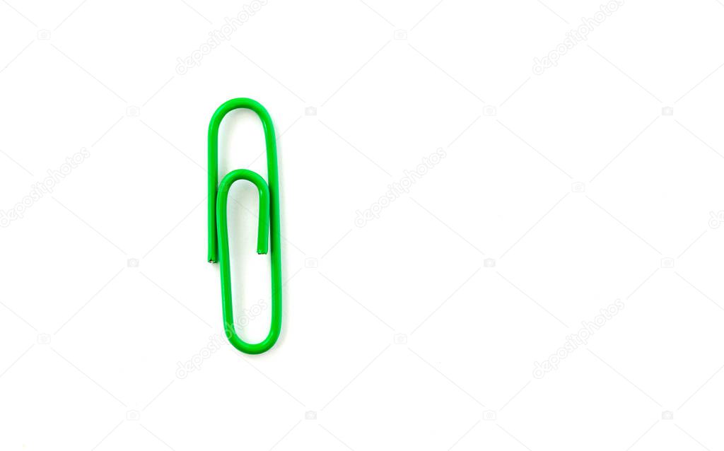 Green paper clip isolated on white background. Close up and top 