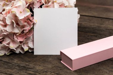 Pastel pembe ortanca çiçekleri, hediye kutusu ve üzerine bir parça kağıt. 