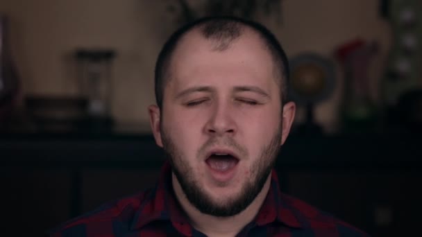 A young guy of European appearance in a plaid shirt closeup yawns. The concept of emotions — 비디오