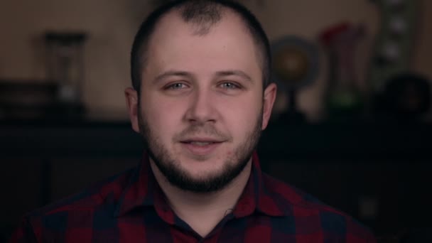 Un jeune homme d'apparence européenne assis sur une chaise dans une chemise à carreaux montre un semblable et le respect dans la caméra — Video