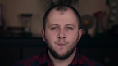 Avrupalı görünümlü genç bir adam ekose gömlekli bir sandalyede oturuyor. Ağzı ısınıyor, kayıt yapmadan önce bir konuşma prova ediyor.