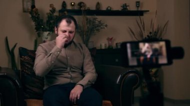 Avrupalı görünümlü genç bir adam burnunu karıştırıyor ve telefonda video çekiyor. Duygular konsepti