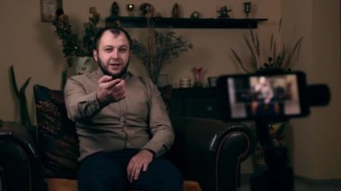 Avrupalı görünümlü bir blogcu olan etkili Sakallı Genç, bir sandalyede oturuyor, telefonda video çekiyor ve videonun altına yorum yazmak istiyor. Sosyal Medya Günlük Kavramı
