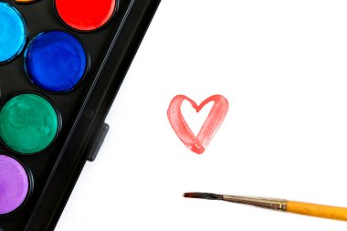 Resim yapmak için fırça ve suluboya boya, kalbi olan bir kağıt. Sevgililer Günü konsepti.