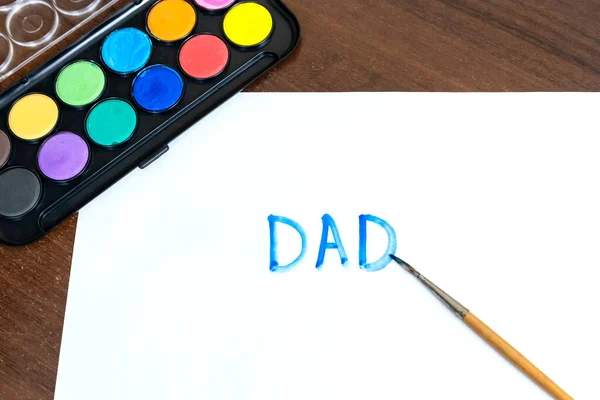Handwritten DAD text with brush and watercolor paints on white background. Father day concept. Family concept