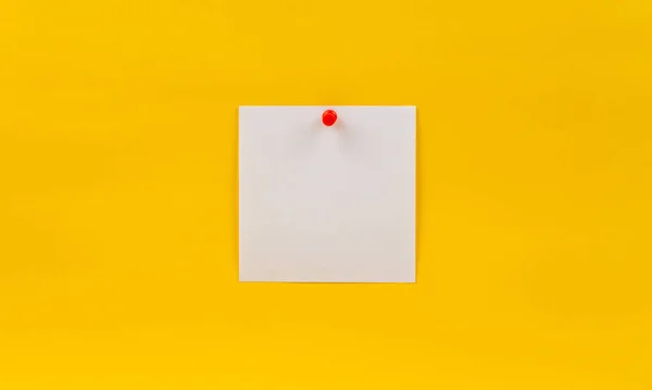 Empty blank white paper note pinned red pin on a yellow background