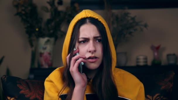 Μπροστά όψη του νεαρού λυπημένου και θυμωμένου κοριτσιού να κάνει συναισθηματική συζήτηση στο τηλέφωνο με το αγόρι της. Δυστυχισμένη απογοητευμένη γυναίκα που μιλάει στο smartphone και τσακώνεται ενώ κάθεται στον καναπέ.. — Αρχείο Βίντεο