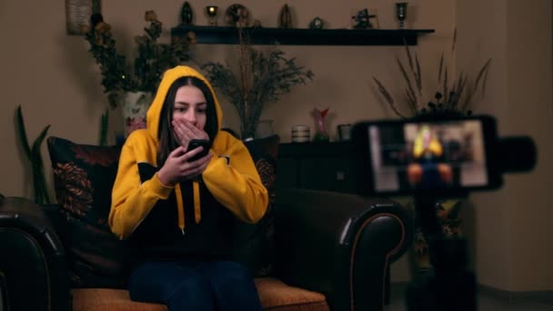 Σοκαρισμένη κοπέλα διαβάζει το μήνυμα μέσω smartphone. Αναστατωμένη νεαρή γυναίκα που κρατάει κινητό στο σπίτι. Άσχημα νέα. Σχόλιο, κινητό. — Αρχείο Βίντεο