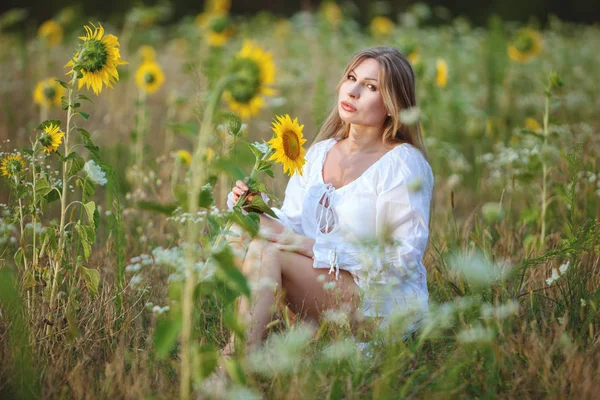 Žena sedí v oblasti mezi slunečnice. — Stock fotografie